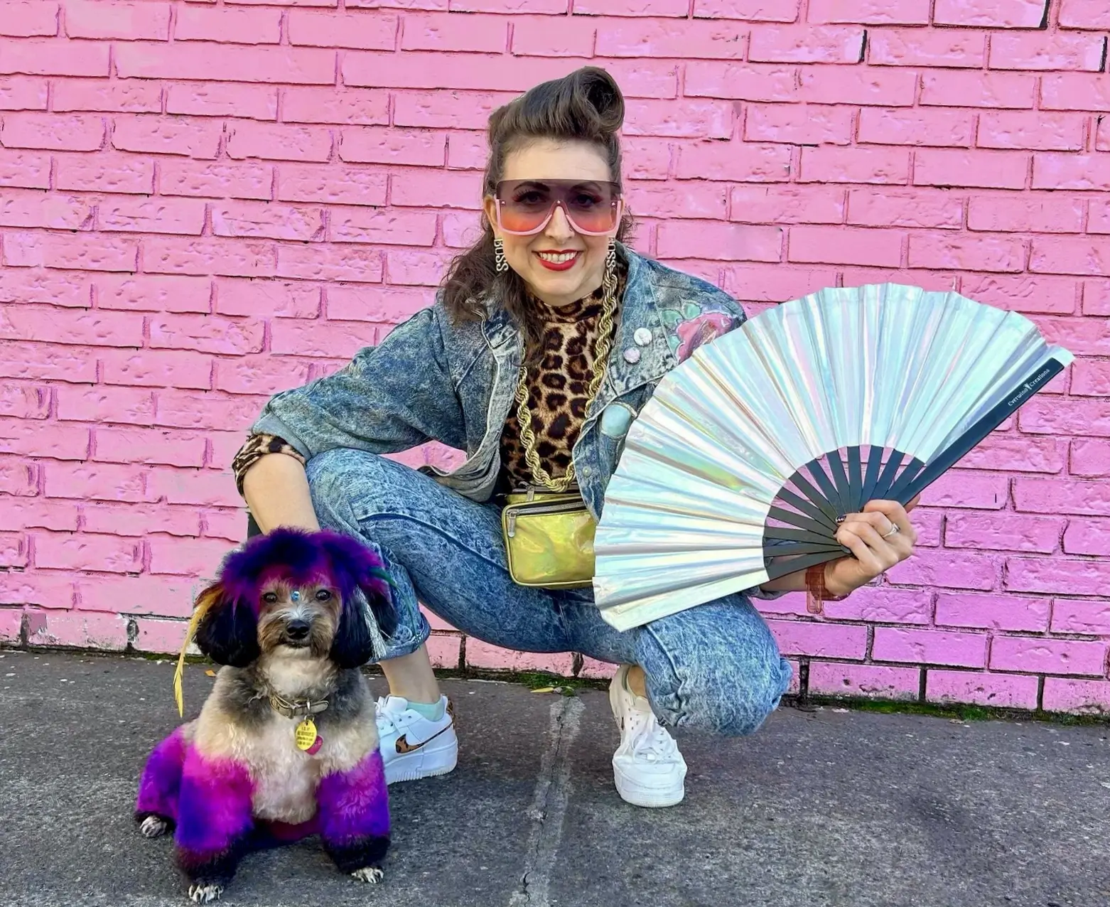 Krista and her yorkichon Chloe in front of a pink brick wall.